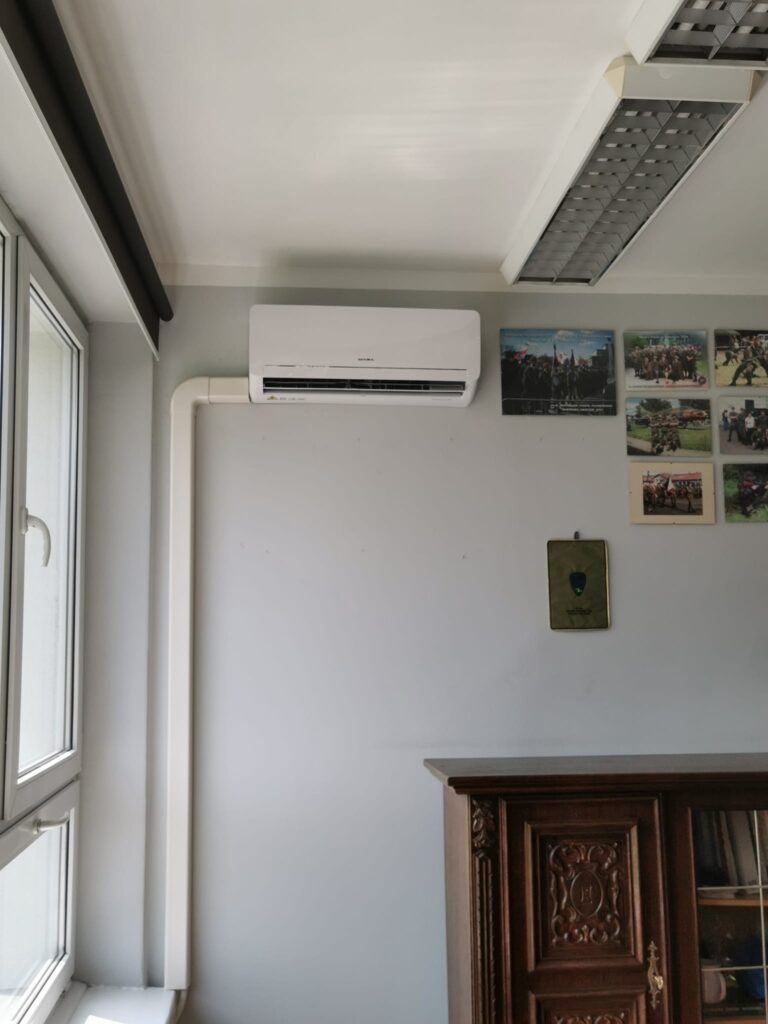 Zdjęcie przedstawia jednostkę wewnętrzną klimatyzatora SEVRA estetycznie zamontowaną przy oknie w gabinecie w szkole z wykorzystaniem koryt maskujących w kolorze białym.